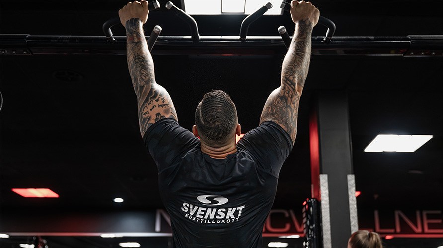 En man bakifr�n, h�nger i ett pull-up-rack. 